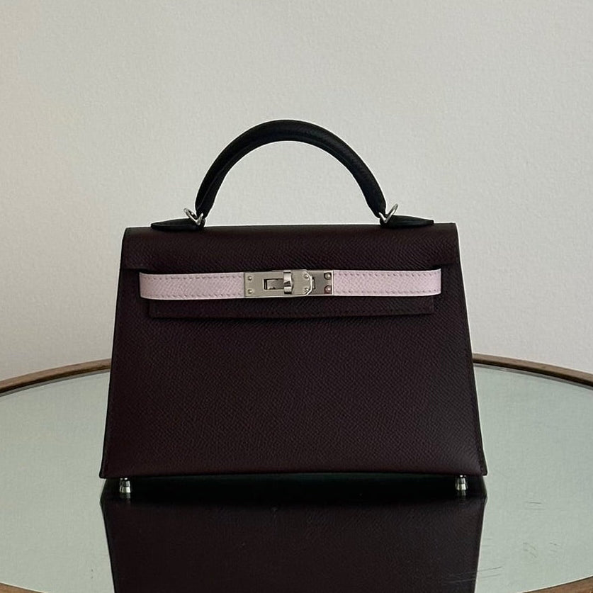 Black handbag with a silver buckle on a round glass table against a plain background