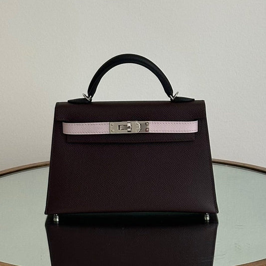 Black handbag with a silver buckle on a round glass table against a plain background